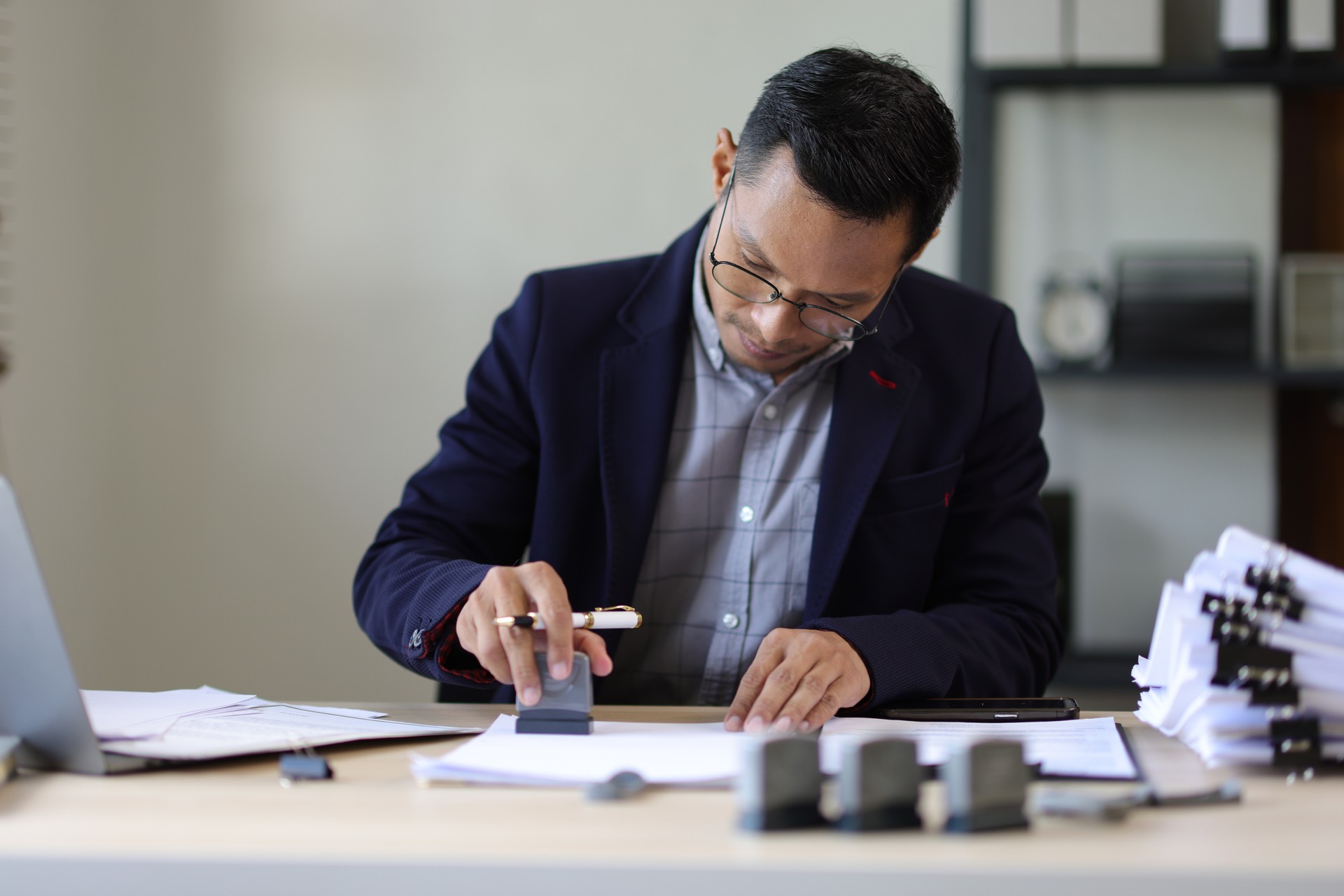 Businessman working on paperwork and stamping approvals, signing documents.